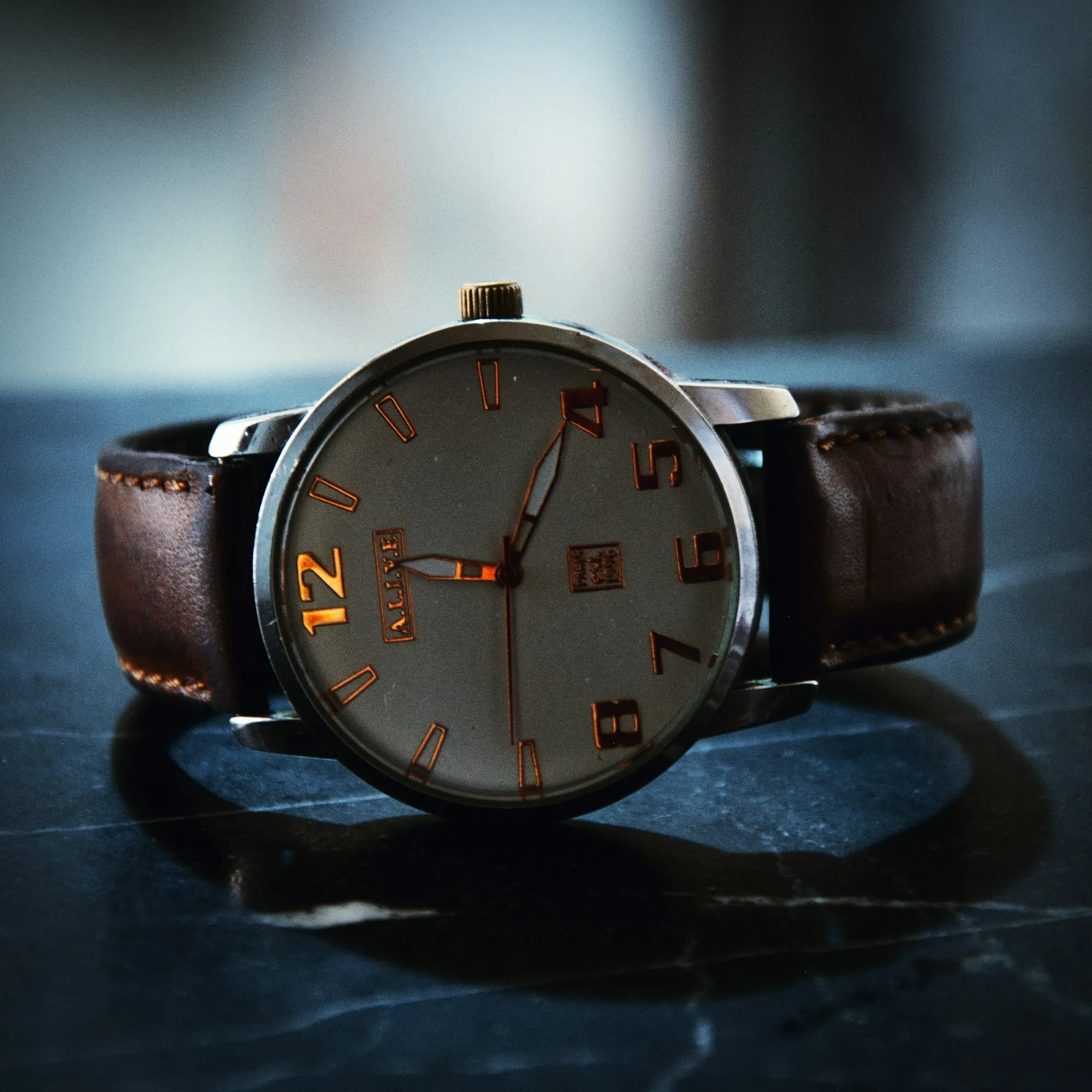 Macro detail of a stitched leather watch strap on a dark watchmaker’s bench